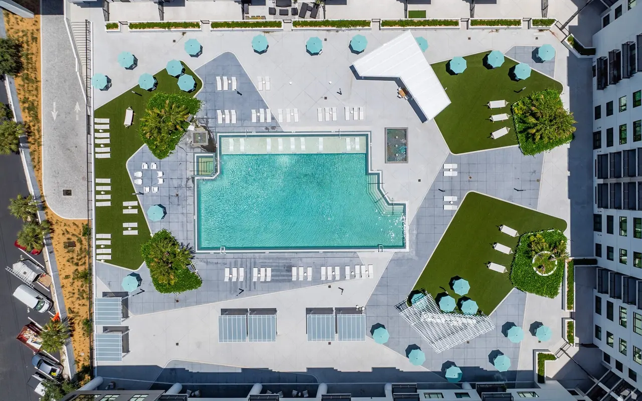Aerial view of a modern pool area with lounge chairs and umbrellas surrounding the pool.