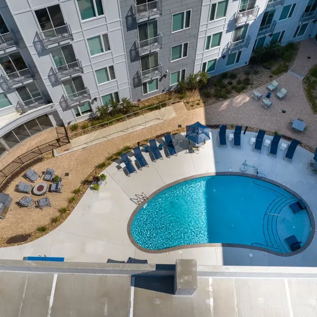 Aerial view of a modern apartment complex with a swimming pool and lounge chairs.