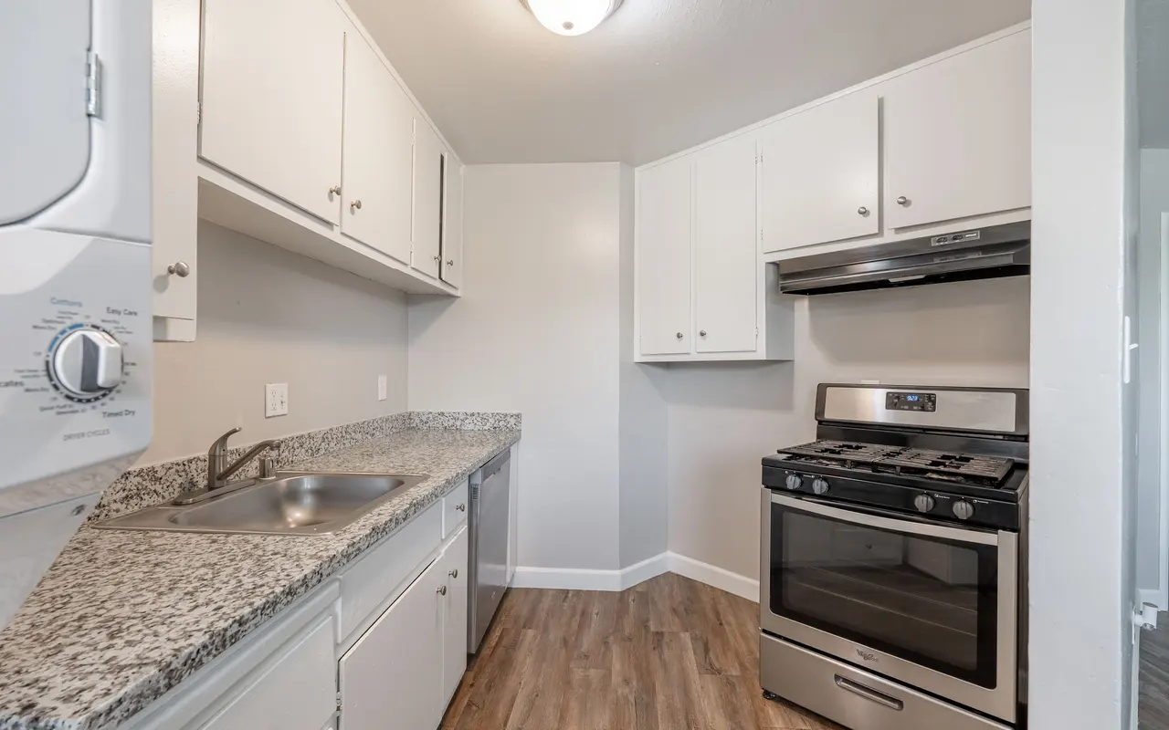 A small kitchen featuring granite countertops, an oven, and white cabinetry.