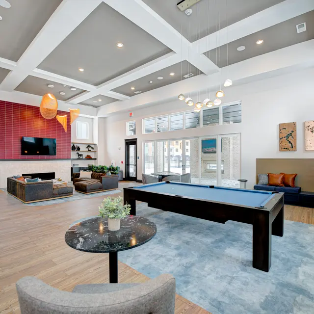 A contemporary lounge area featuring a pool table, comfortable seating, and modern decor.
