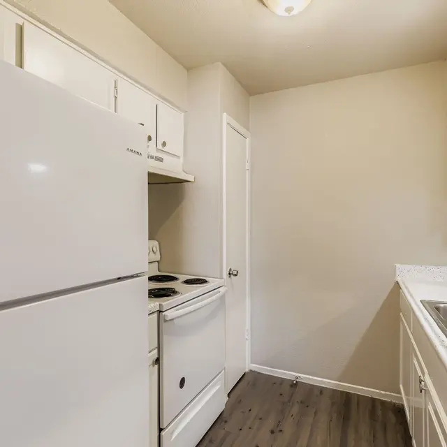A small kitchen featuring white appliances, including a refrigerator and stove, with light-colored cabinets and countertops.
