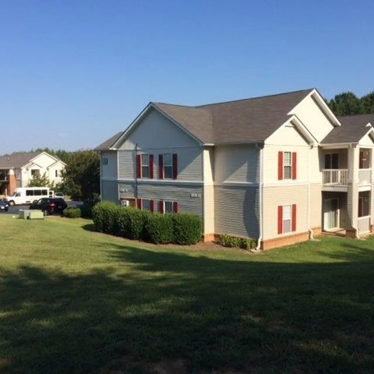 View of an apartment complex with green lawn and clear blue sky.