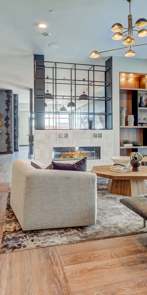 Modern living room with sleek furniture, a stylish coffee table, large windows, and an open kitchen area, featuring warm wooden floors.