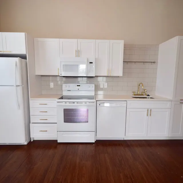 Modern Kitchen Design A modern kitchen featuring white cabinetry, a stainless steel stove, microwave, and dishwasher. The kitchen includes a white refrigerator and a golden faucet, set against a light tiled backsplash.