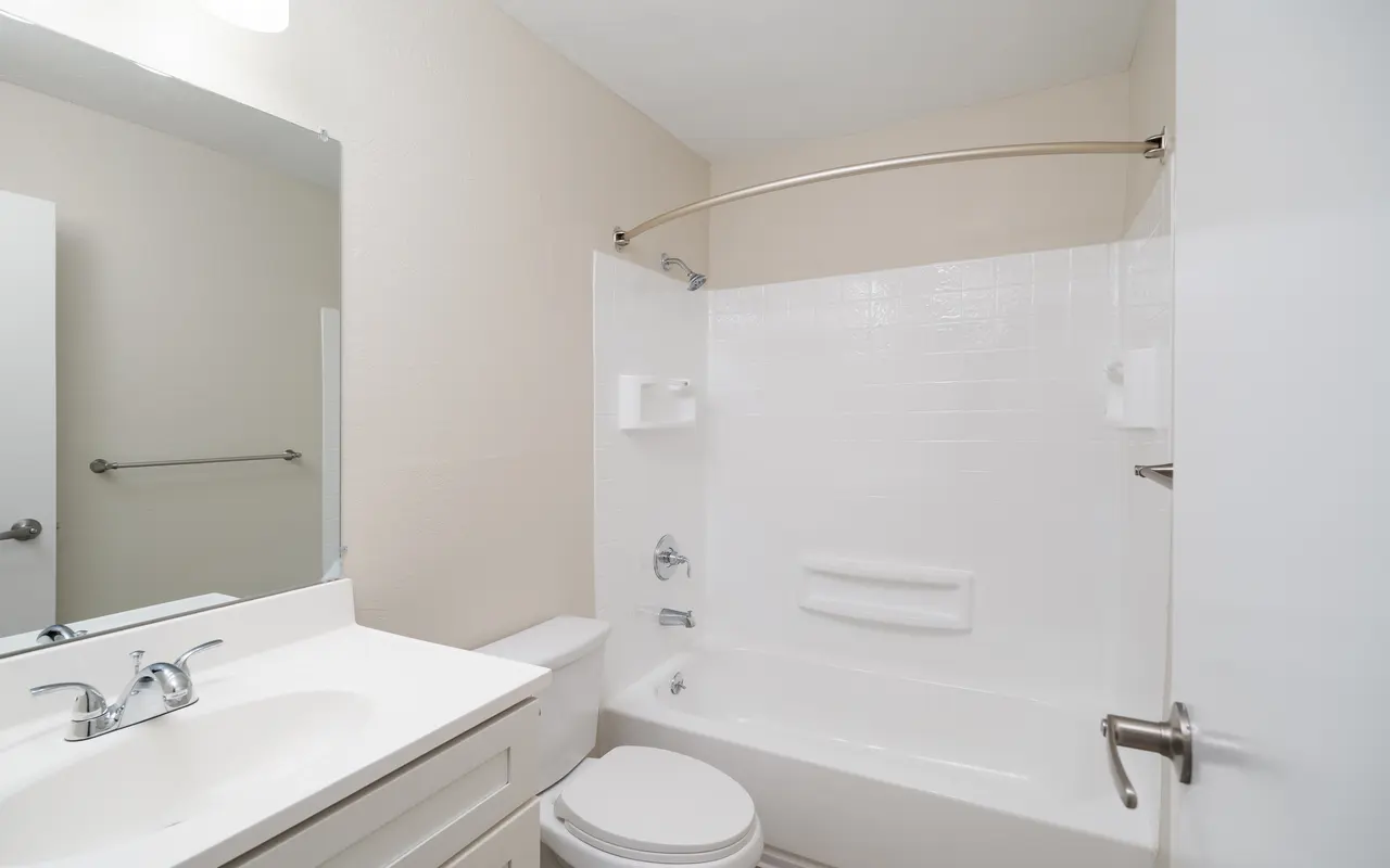 Modern bathroom with a bathtub, toilet, and sink, featuring a neutral color palette and contemporary fixtures.