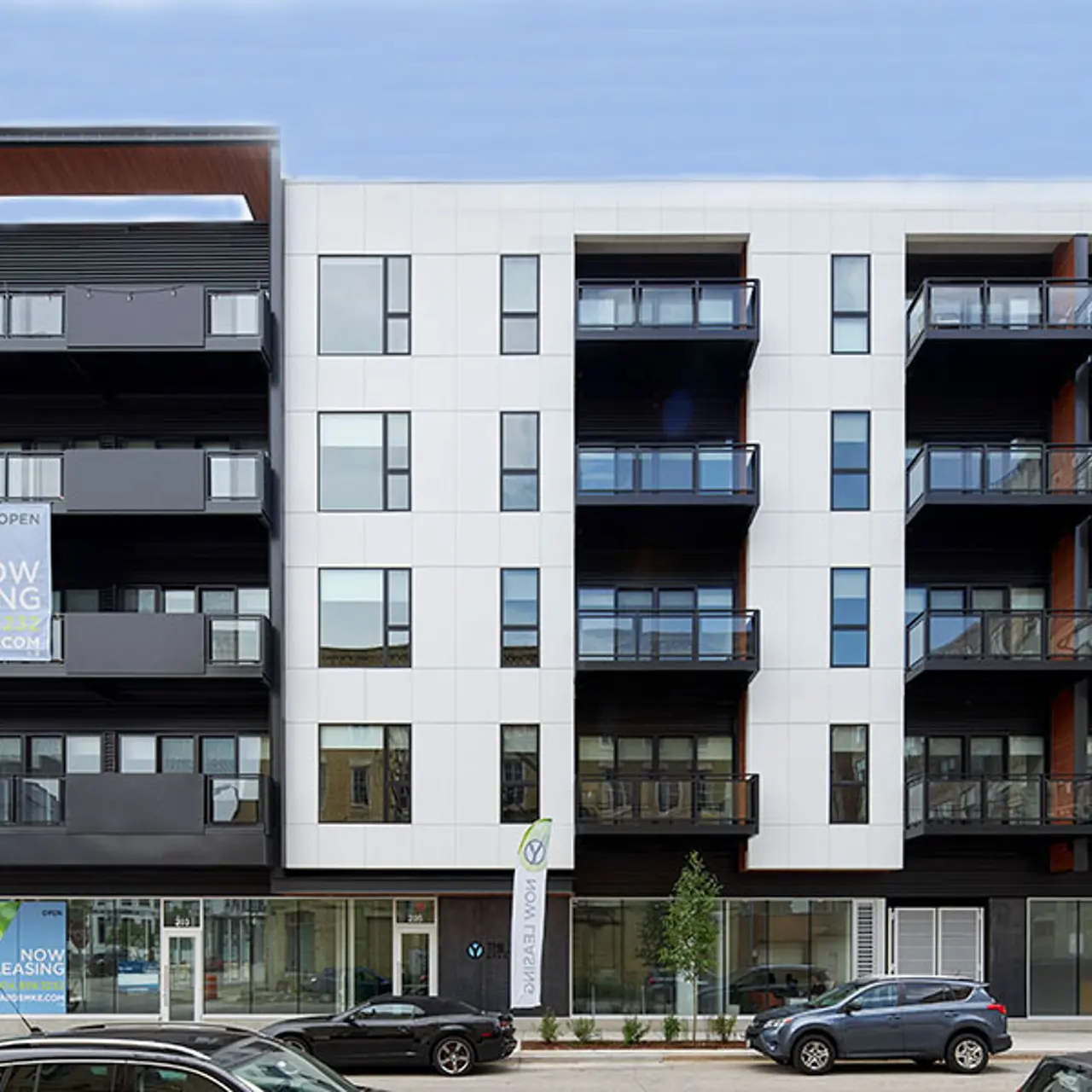 Newly Built Apartment Complex A contemporary apartment building with multiple balconies and large windows, featuring a leasing sign in front.