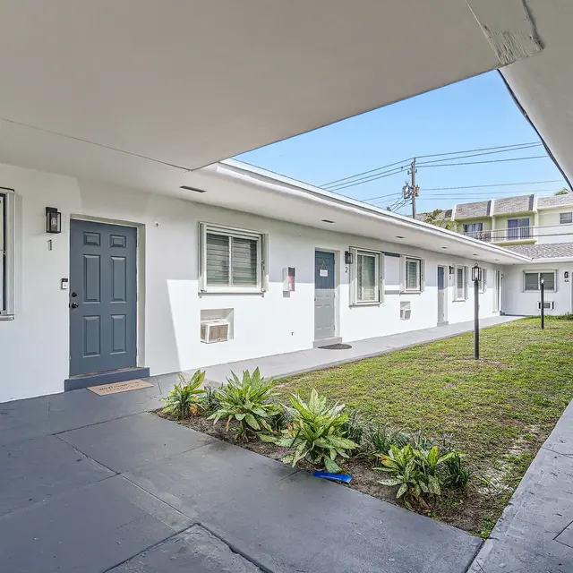 View of the courtyard in an apartment complex showing a grassy area, several doors, and pathways.