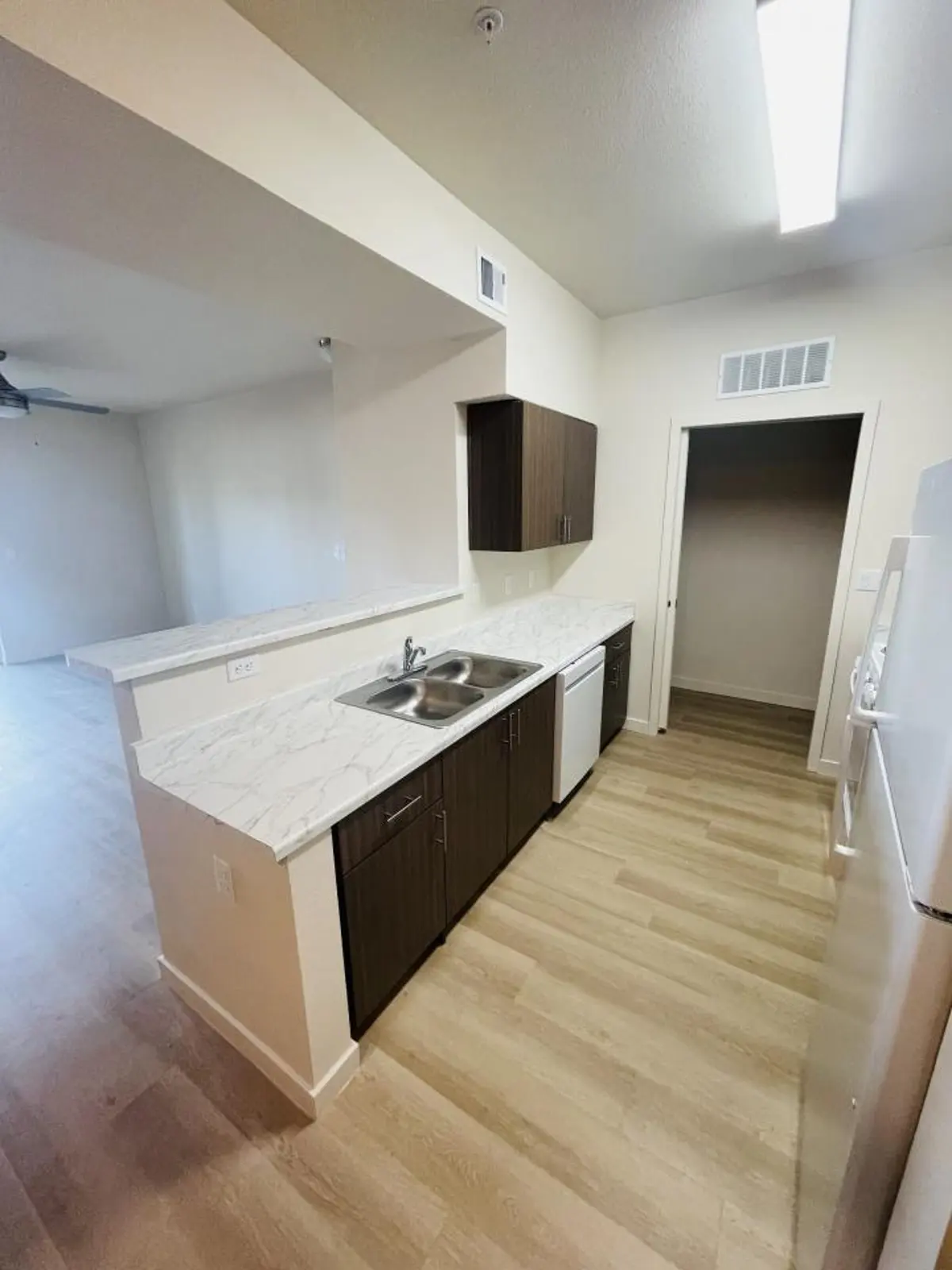 Kitchen sink and breakfast counter beside open closet.