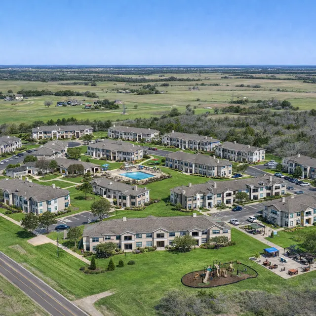 Aerial View of Apartment Complex Aerial view of a residential apartment complex surrounded by green fields and a road.