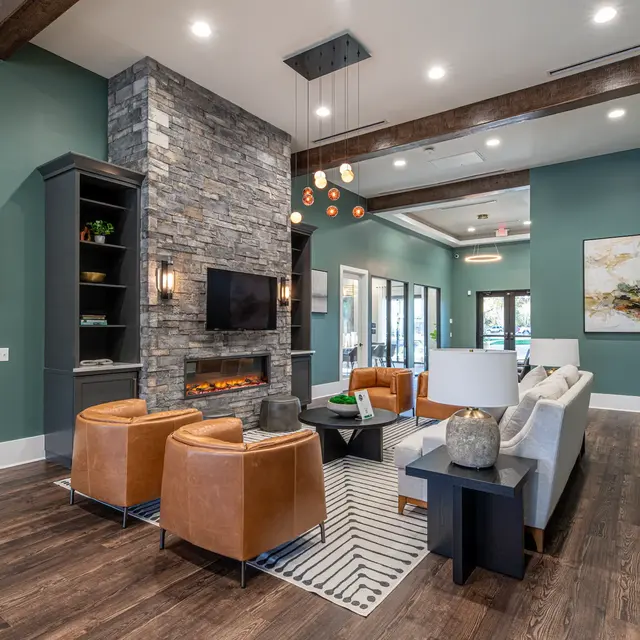 A modern living room featuring a stone fireplace, green walls, and stylish furniture including brown leather chairs and a gray sofa.