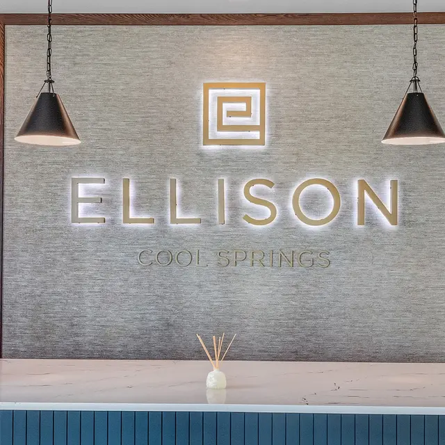 Reception area featuring a modern countertop and a decorative wall with the words 'ELLISON COOL SPRINGS' illuminated above it.
