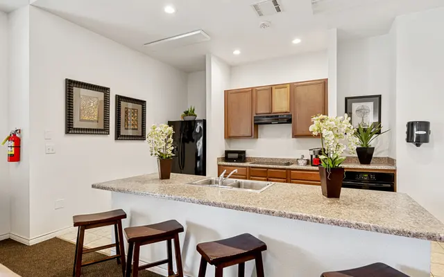 Modern Kitchen Interior A modern kitchen featuring a central island with bar stools, wooden cabinets, and appliances. Decorative floral arrangements add a touch of elegance.