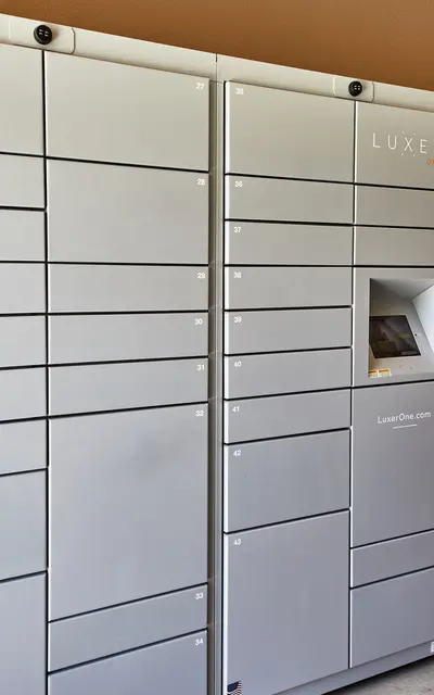 A row of gray storage lockers arranged in columns, with a small access point highlighted in the center. Each locker features numbers but is otherwise unmarked.