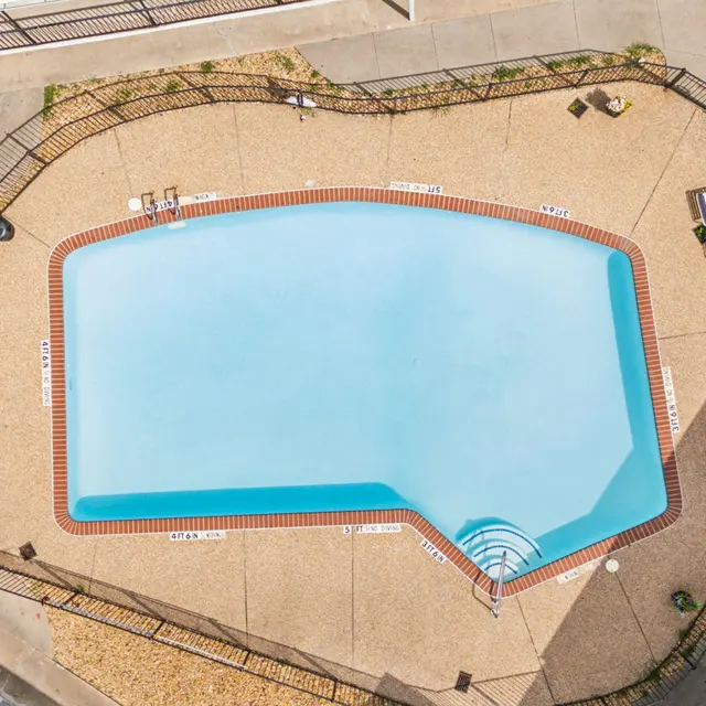 Aerial view of a swimming pool surrounded by a paved area and sun loungers.