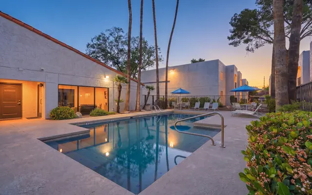 A serene pool area at sunset with palm trees and lounge chairs.