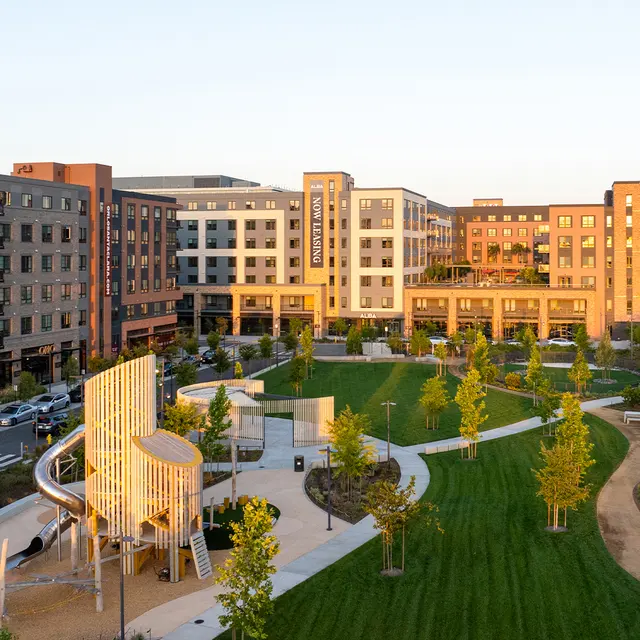 Aerial view of a modern apartment complex surrounded by landscaped green areas and walking paths.
