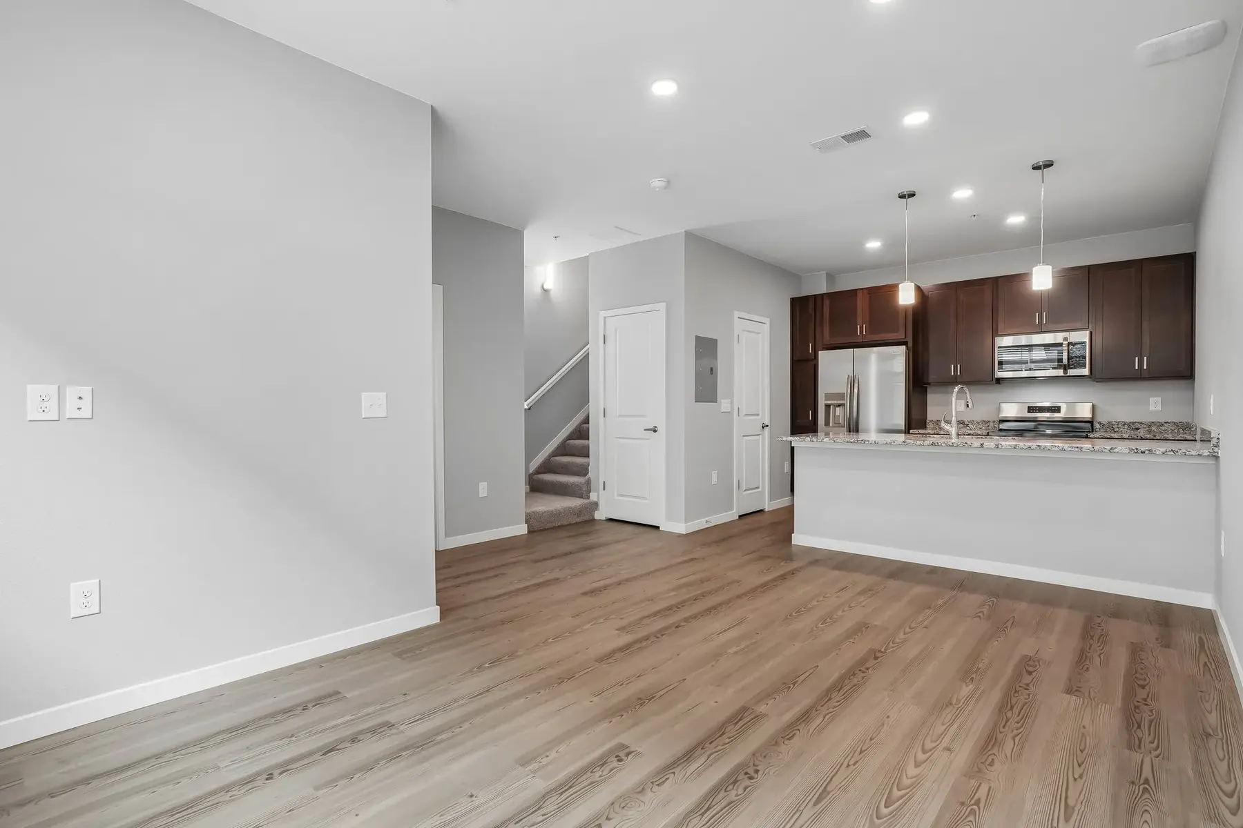 Spacious Modern Apartment Living Area A spacious modern apartment interior with wooden flooring, gray walls, and a kitchen area with dark wood cabinets.