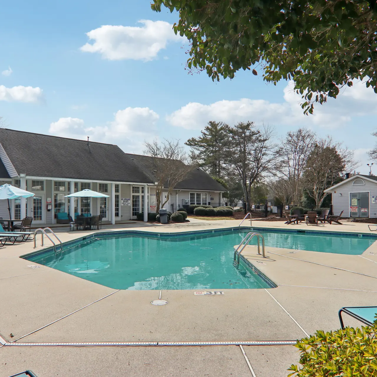A serene outdoor swimming pool area surrounded by lounge chairs and umbrellas on a sunny day.