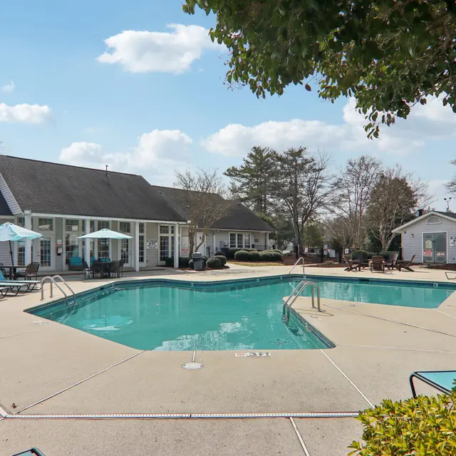 A serene outdoor swimming pool area surrounded by lounge chairs and umbrellas on a sunny day.