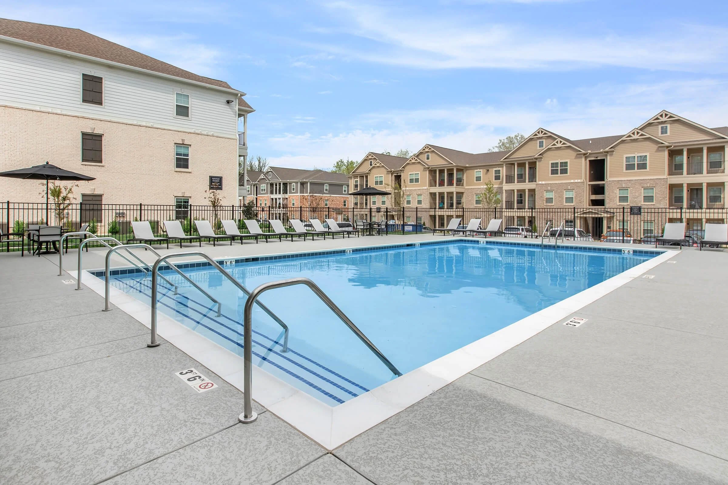 Modern Apartment Pool Area Swimming pool area surrounded by lounge chairs and residential buildings.