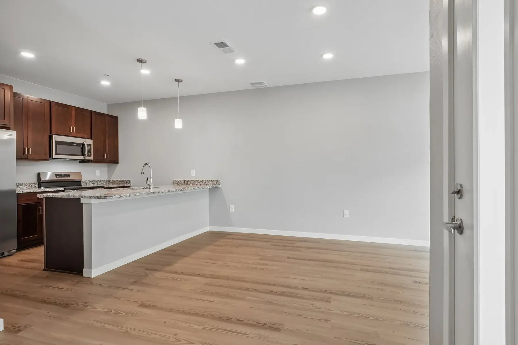 Modern Kitchen and Living Space Open concept kitchen and living area featuring modern appliances and wooden flooring.