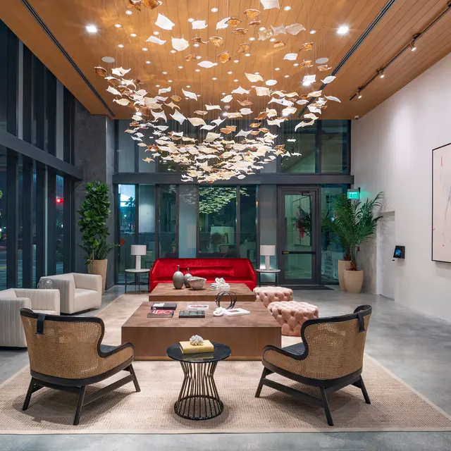 A modern lobby featuring a striking ceiling installation, with plush seating arrangements and decorative plants.