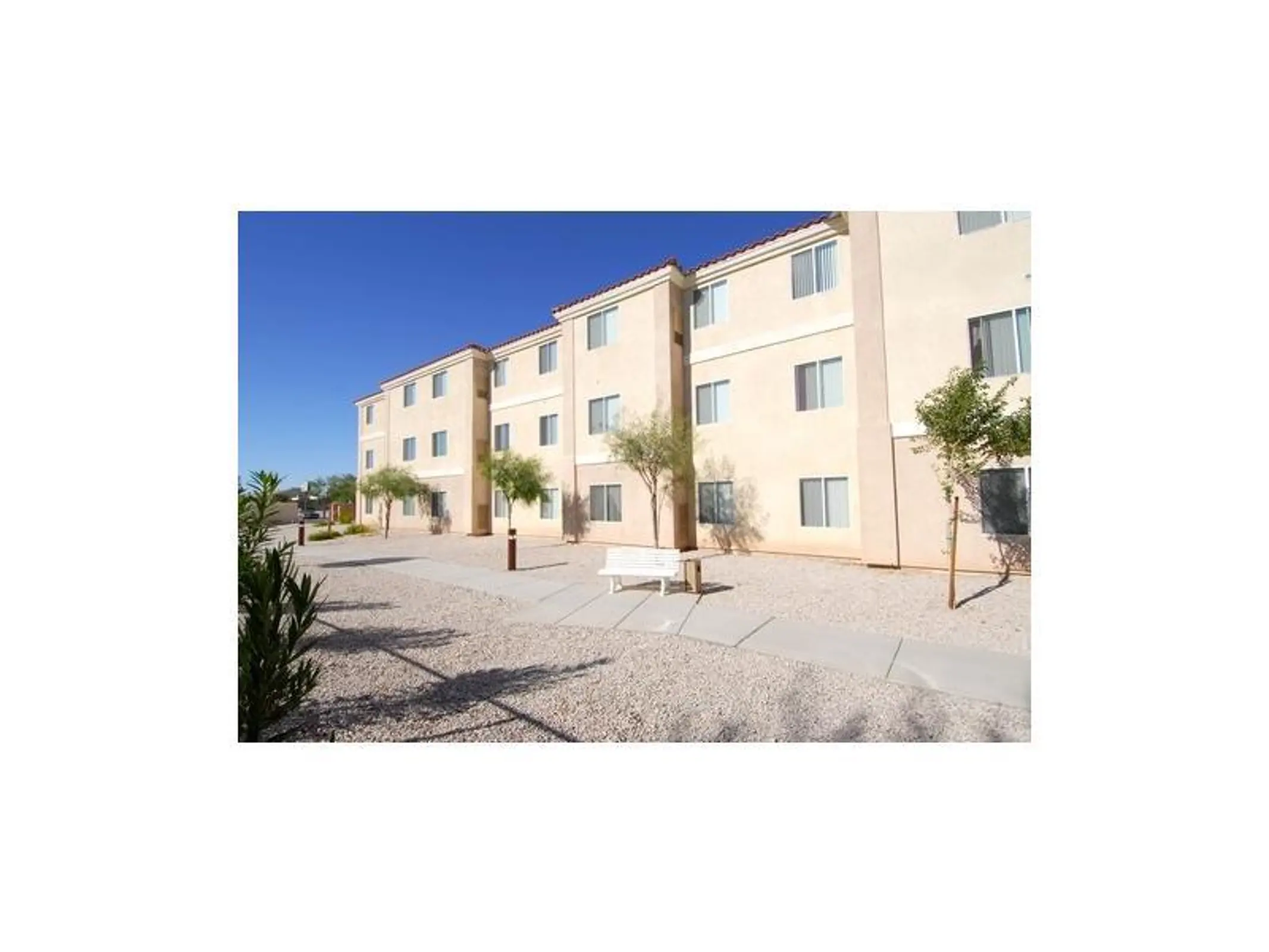 Three-story apartment exterior beside gravel landscaping and a walkway.