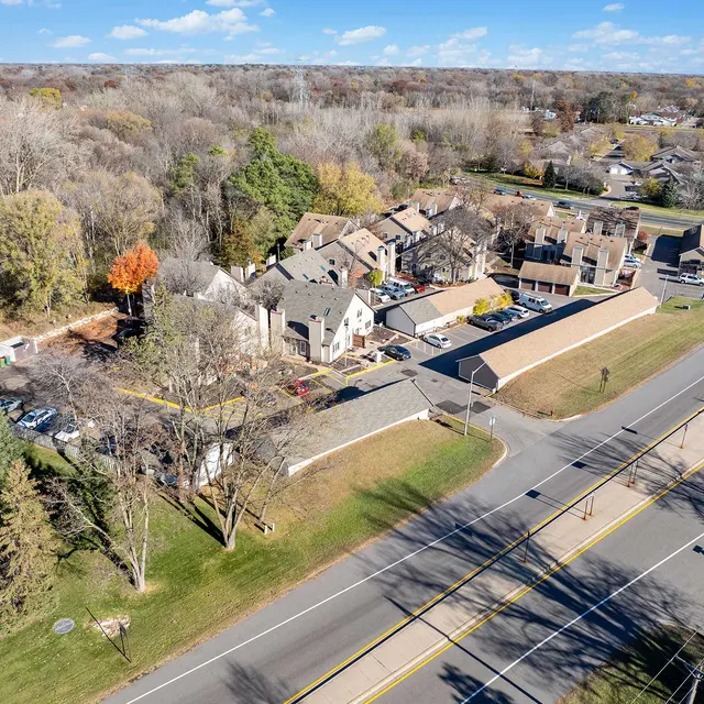 Aerial view of a residential area with houses, trees, and a road.