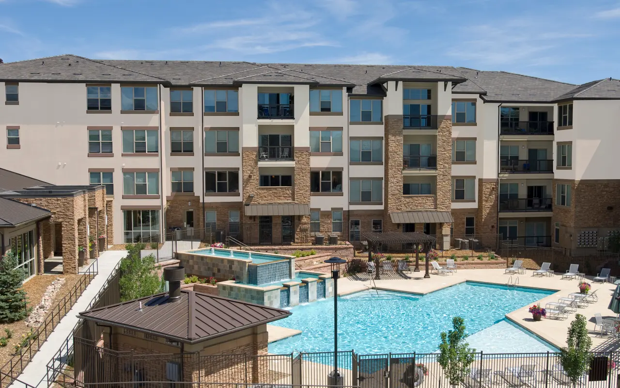 View of a modern apartment complex with a swimming pool and lounge area