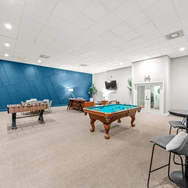 Spacious game room featuring a pool table, foosball table, and various seating arrangements.