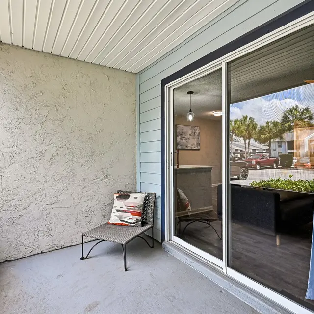 Cozy Porch with Outdoor View A cozy porch area with a minimalist design. It features a simple chair and a glass sliding door reflecting the outdoors.