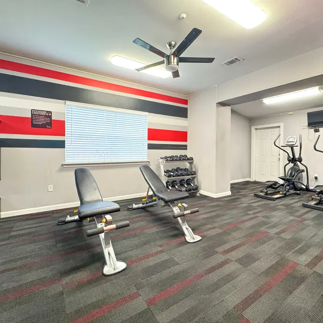 Interior of a modern gym featuring exercise equipment and a color scheme of red, black, and gray.