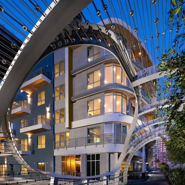 Modern Residential Architecture at Dusk Modern residential building at dusk, featuring large windows and unique architectural features, surrounded by greenery and decorative lighting.