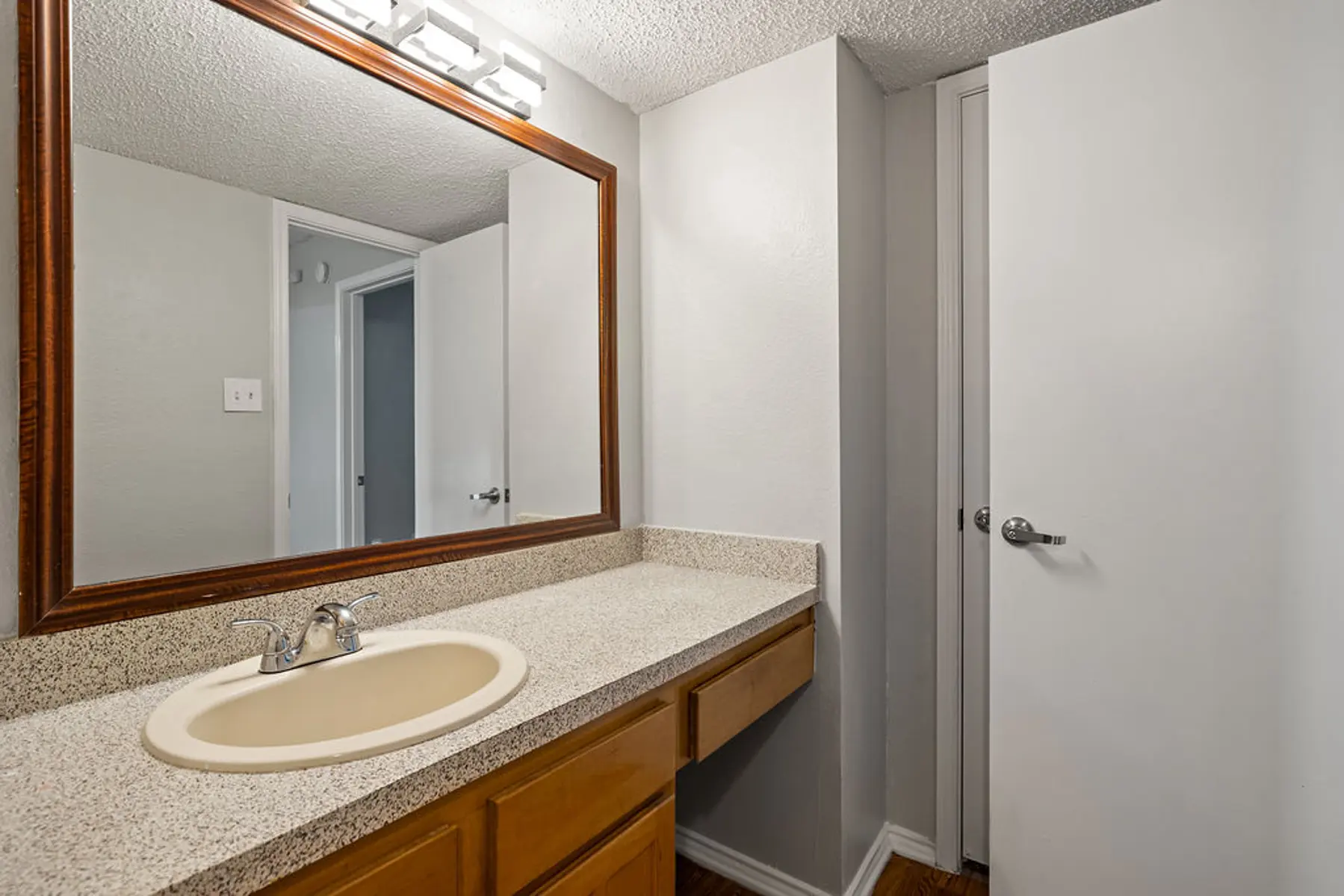 Modern Bathroom Interior A modern bathroom with a large vanity, mirror, and door leading to a closet. The walls are painted light gray, and the counter features a beige sink.
