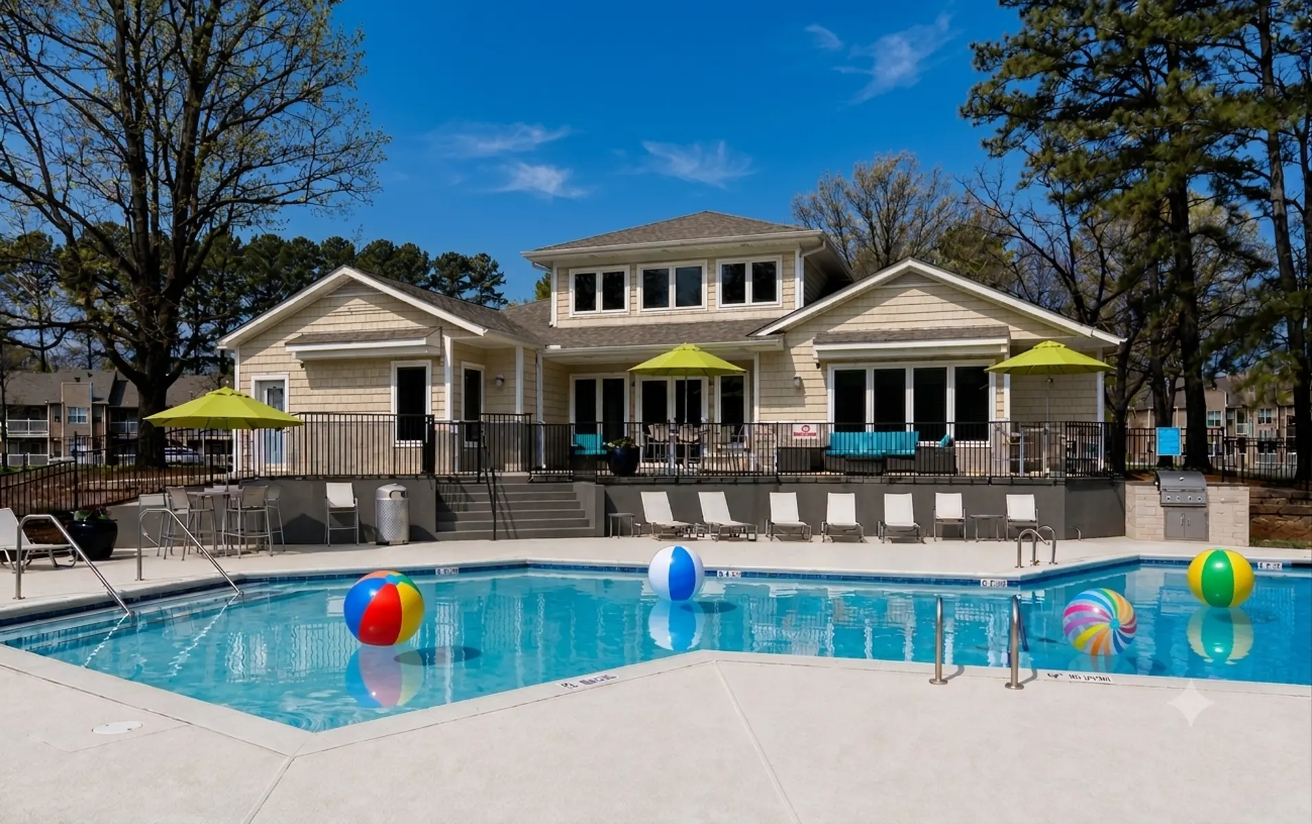A community pool area with colorful beach balls and green umbrellas, featuring a large house in the background.