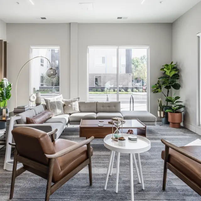 Contemporary Living Room Design A modern living room featuring a sectional sofa, two armchairs, a round white coffee table, and large windows letting in natural light. Decorative plants and stylish decor are present.