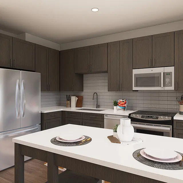 A modern kitchen featuring dark wood cabinetry, stainless steel appliances, and a white countertop island with plates and a vase. The space is well-lit and has a clean, contemporary design.