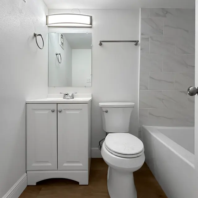 Contemporary Bathroom Interior A modern bathroom featuring a white cabinet underneath a mirror, a toilet, and a bathtub with a tiled wall.