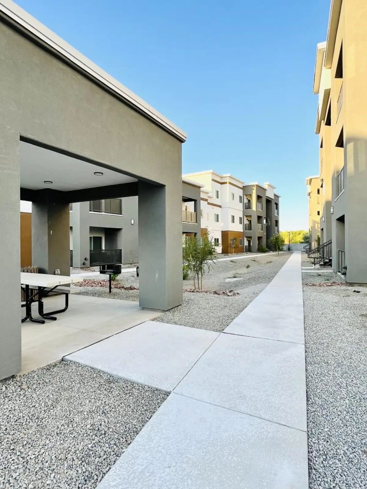 Covered picnic table and grill beside walkway.