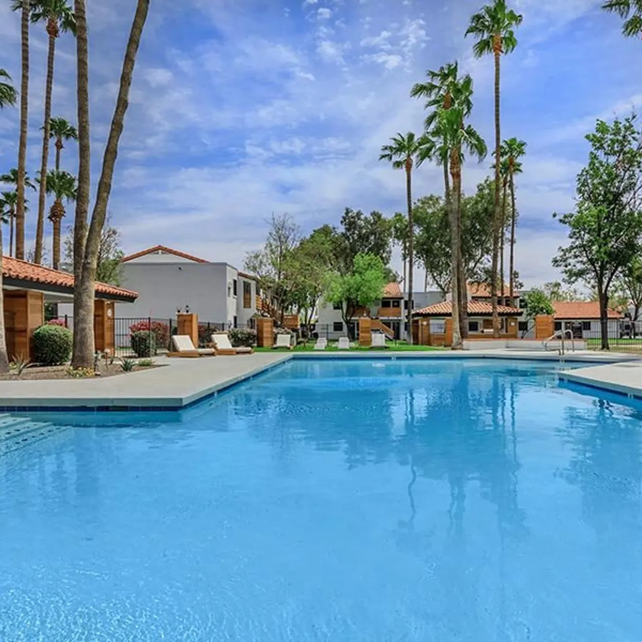 A serene swimming pool area surrounded by palm trees and residential buildings.