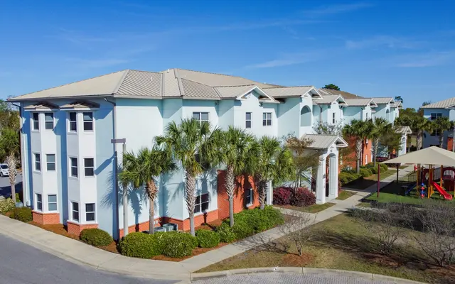 Modern Apartment Complex with Playground Aerial view of a modern apartment complex with palm trees and a playground.