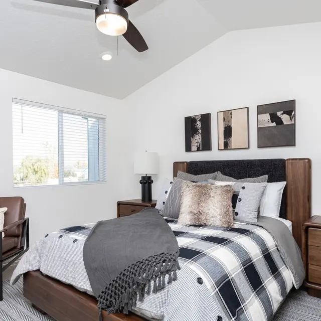 A modern bedroom featuring a cozy bed with a checkered blanket, a stylish armchair, and contemporary decor.