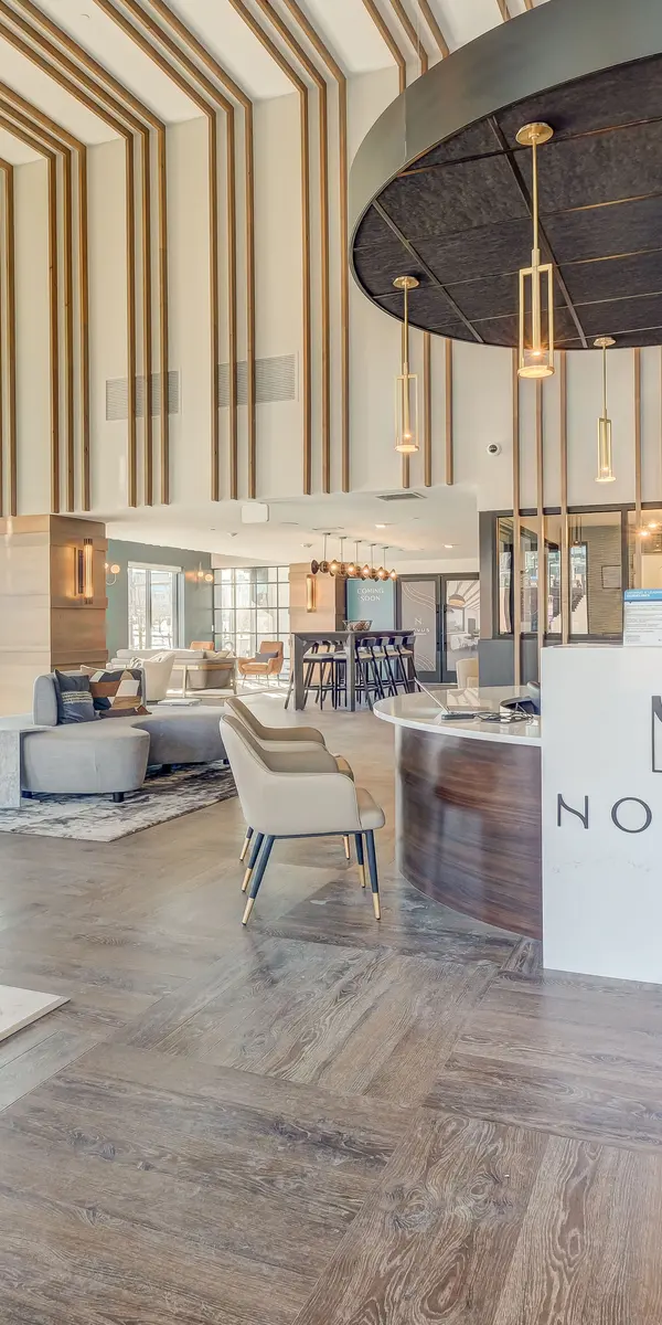 Modern lobby with tall ceilings, stylish seating, a circular reception desk with the "NOVUS" logo, and large windows letting in natural light.