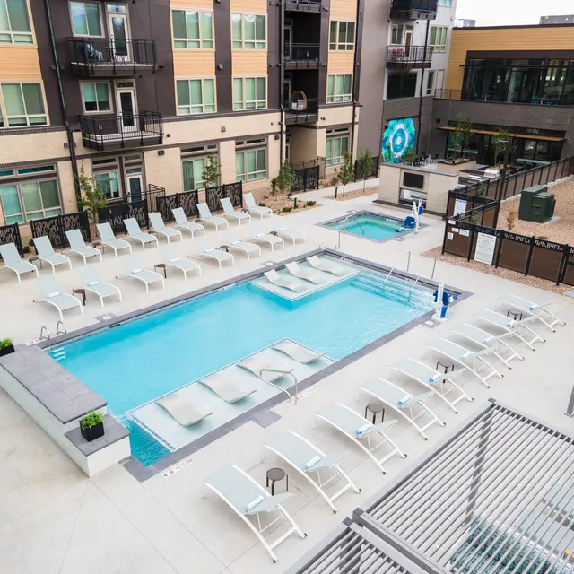 Modern Apartment Pool Area A modern outdoor pool area featuring a swimming pool and hot tub, surrounded by lounge chairs and landscaping.