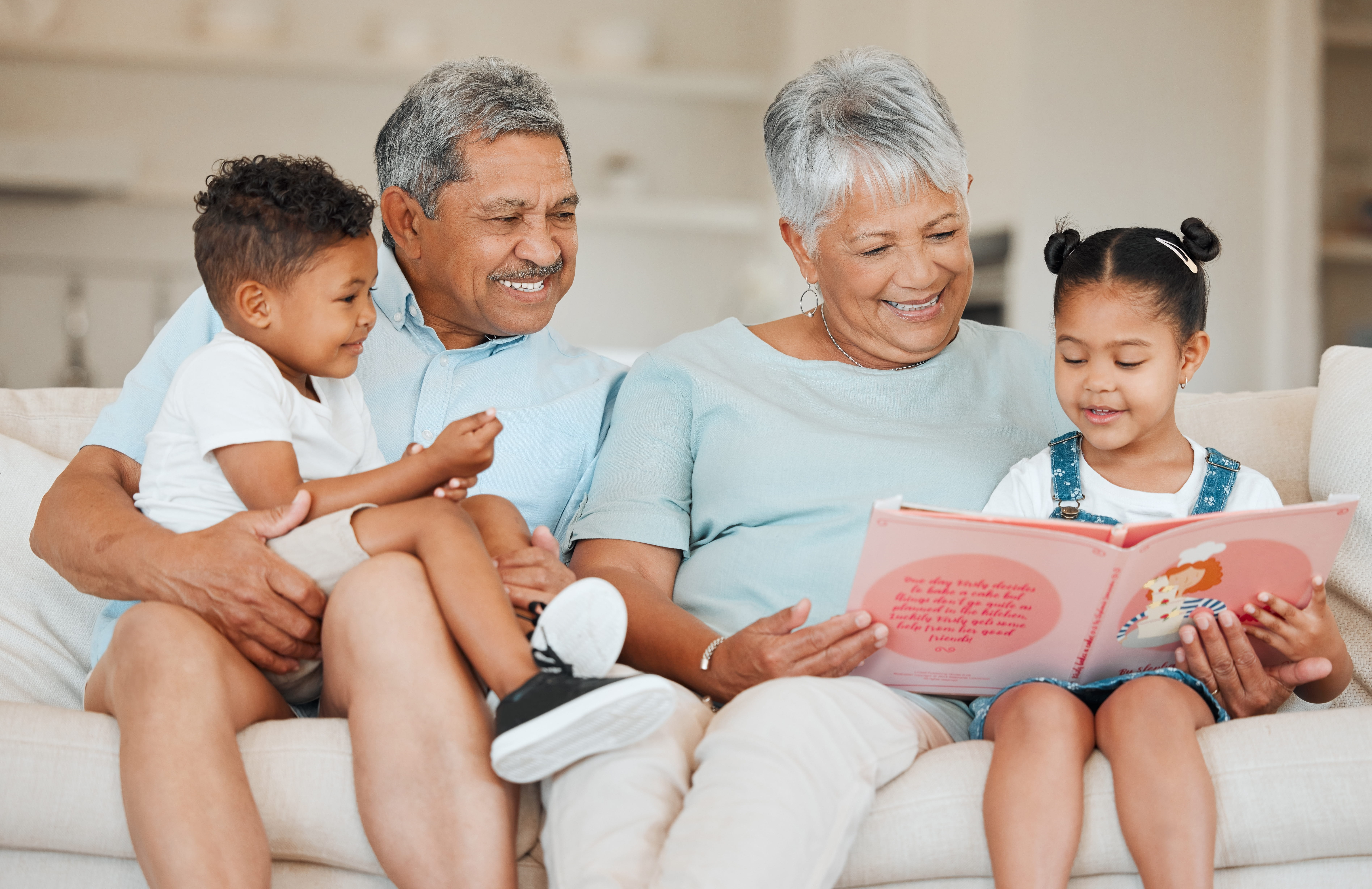 Family Bonding through Storytime A joyful family scene with grandparents and two children reading a book together on a couch.