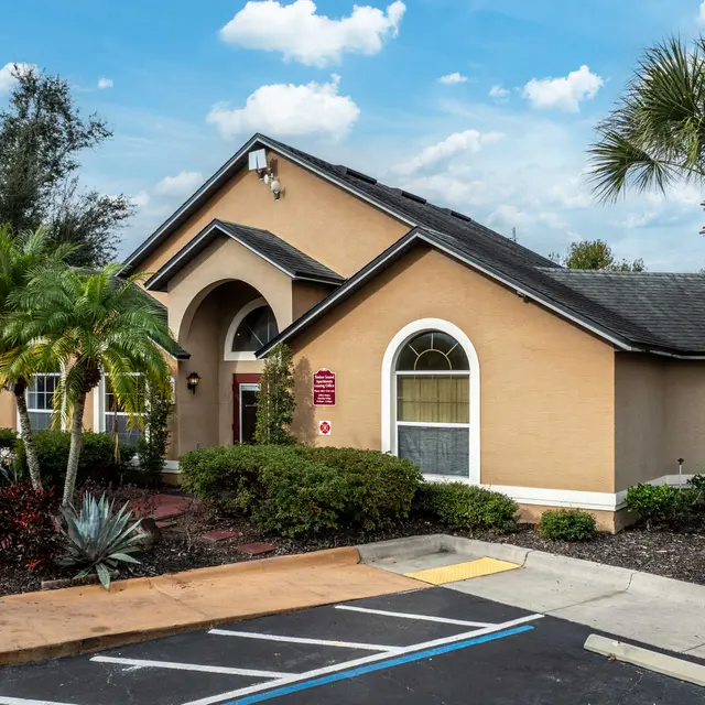 A sunny view of a community center surrounded by lush greenery and palm trees.
