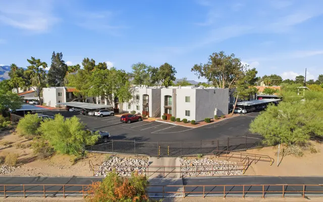 Aerial view of an apartment complex with parking spaces and surrounding greenery.