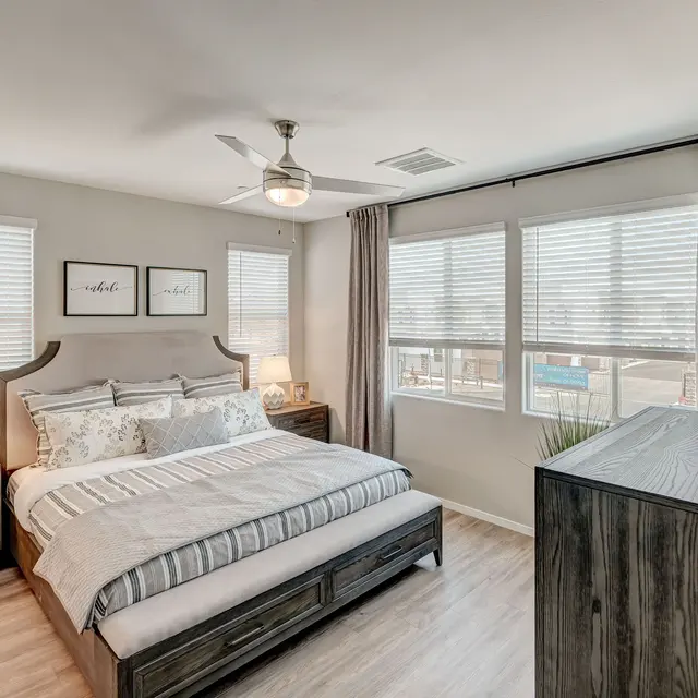 Cozy bedroom with a king-size bed, wooden furniture, large windows, and soft gray curtains, creating a serene atmosphere.