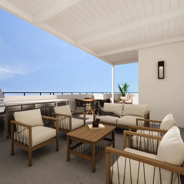 Stylish Outdoor Living Area A spacious outdoor living area with comfortable seating, a wooden table, and a barbecue grill under a covered patio.
