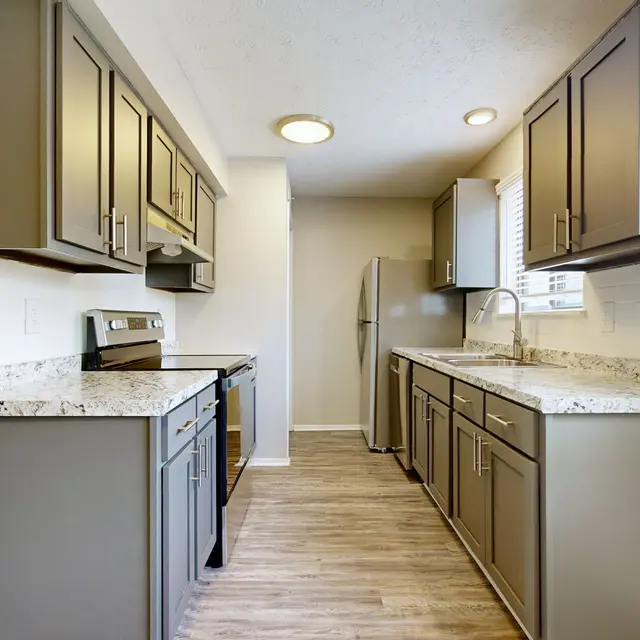The Hideaway -  A modern kitchen featuring gray cabinets, granite countertops, and stainless steel appliances. The space is well-lit with natural light.